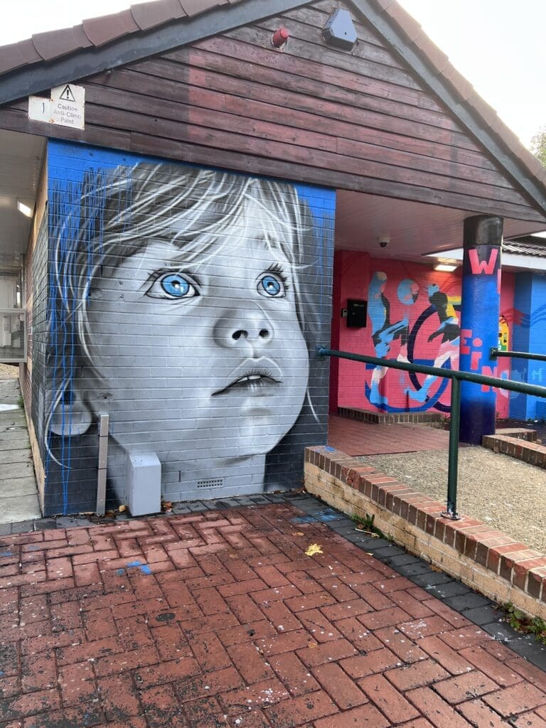 A colorful mural of a child's face displayed on a weathered brick wall.